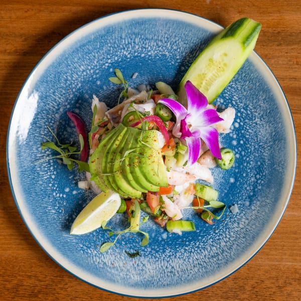California Tacos Cantina's ceviche with avocado, lime, cucumber, and a purple orchid on a blue plate.